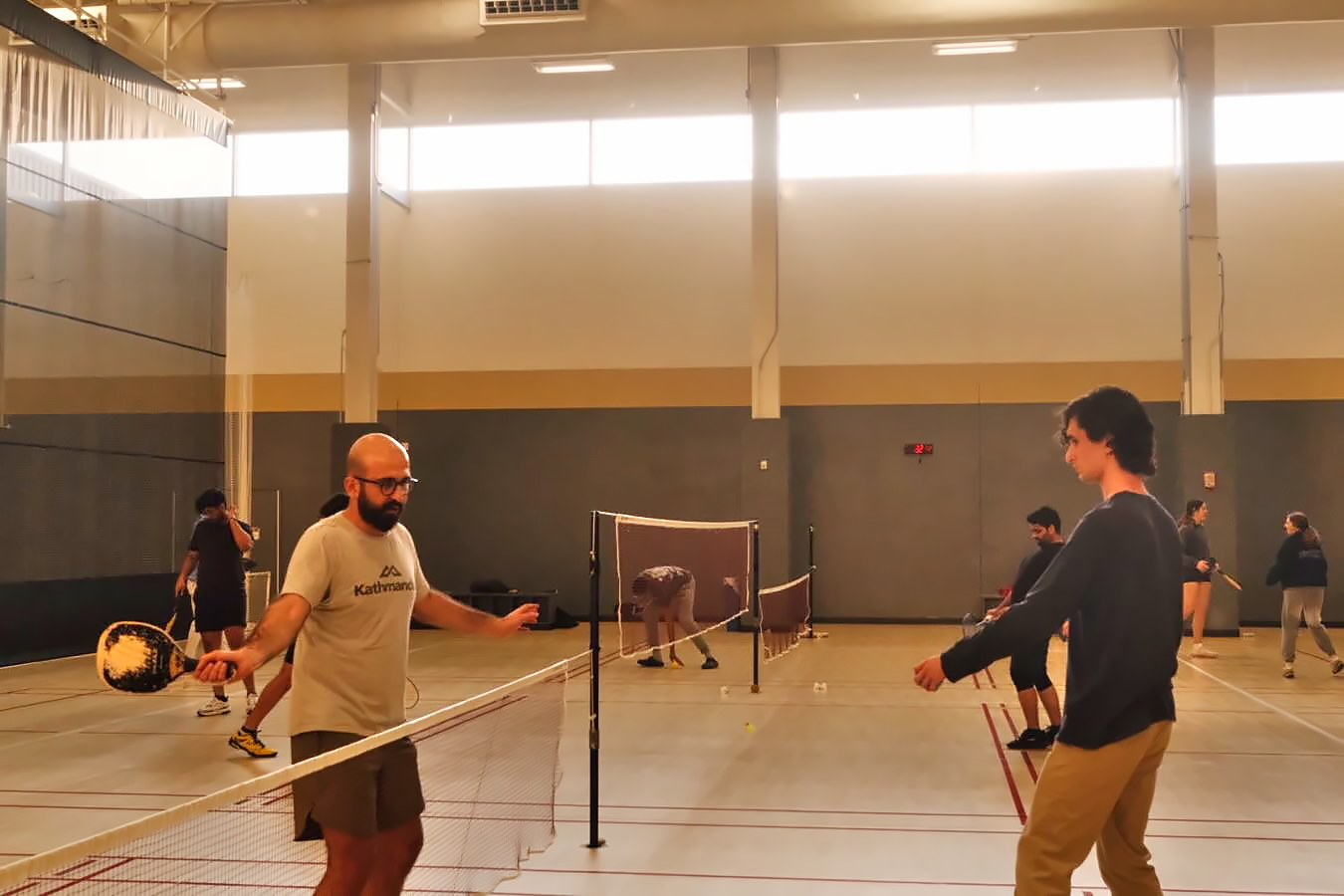 Two members mid-rally on the pickleball courts during a weeknight session