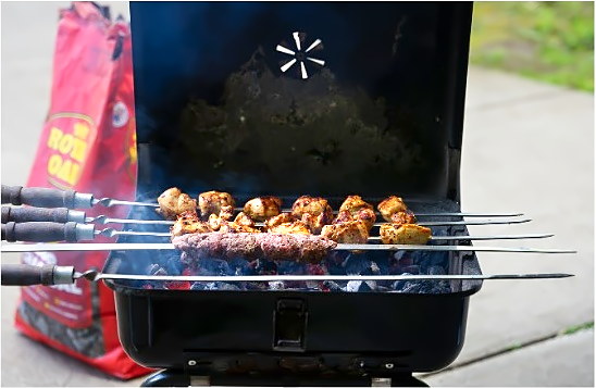 Pork and chicken skewers laid across the charcoal at a club cookout